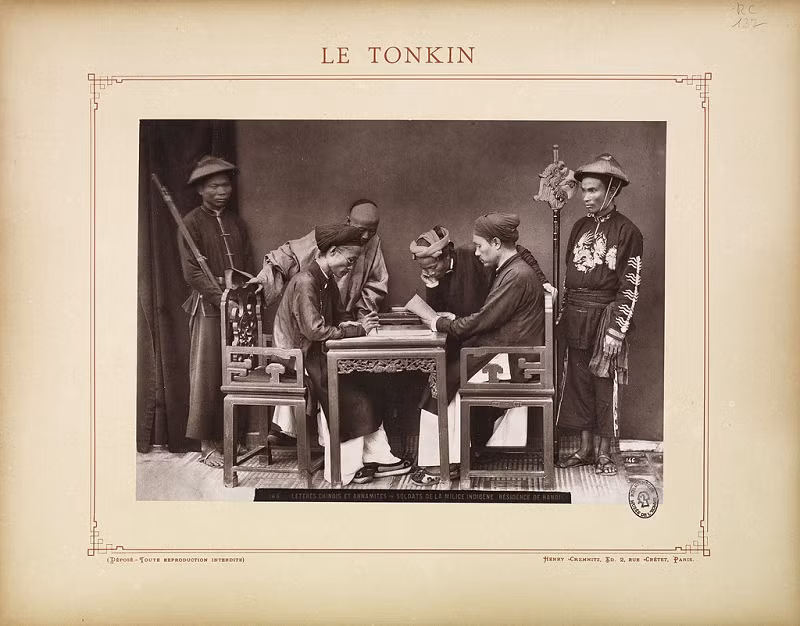 Ảnh hai ông quan xem xét các văn thư, xung quanh là vài thường dân và binh lính.