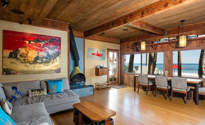 Không gian tầng một hầu như được ốp gỗ thô hoàn toàn đem lại cảm giác mộc mạc, bình dị, và ấm cúng. Phòng khách thoáng đãng được điểm xuyến một ít màu sắc sặc sỡ từ những đồ nội thất.