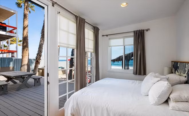 Phòng ngủ tầng 1, bao quanh bởi cảnh sắc đại dương, được kết nối với hiên nhà bằng những cánh cửa mang phong cách nước Pháp.