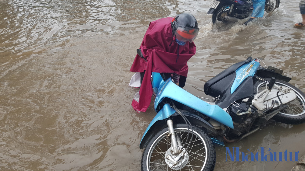 Một phụ nữ bị đổ xe đi trên đường ngập.