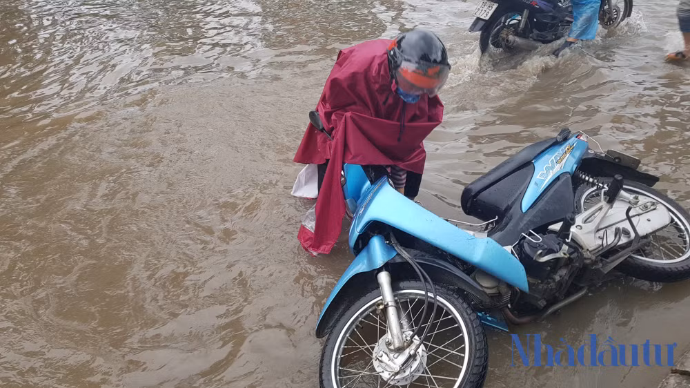 Một phụ nữ bị đổ xe đi trên đường ngập.