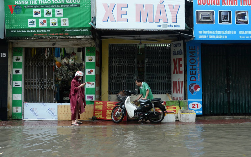 Cuộc sống của nhiều hộ dân tại đoạn phố Trần Bình đã bị ảnh hưởng, nhiều cửa hàng phải đóng cửa và tìm cách che chắn không cho nước ngập tràn vào nhà.
