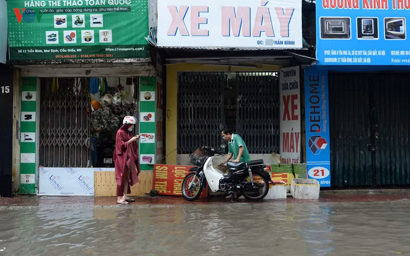 Cuộc sống của nhiều hộ dân tại đoạn phố Trần Bình đã bị ảnh hưởng, nhiều cửa hàng phải đóng cửa và tìm cách che chắn không cho nước ngập tràn vào nhà.