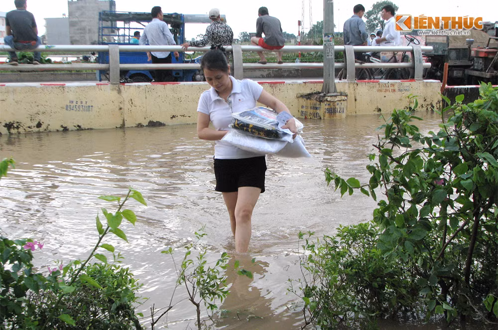 Do không thể di chuyển phương tiện ra khỏi tòa nhà nên người dân nơi đây chọn phương án mua hàng online. Trong ảnh là một phụ nữ sống tại tầng 23 của tòa nhà lội qua điểm ngập sâu để nhận hàng từ người giao hàng vào chiều nay 26/5.