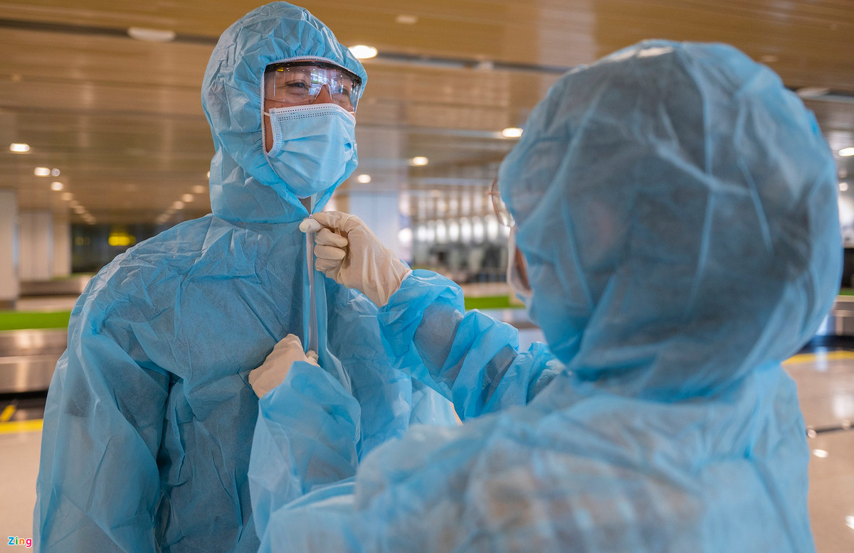 Nhân viên phục vụ đón các hành khách từ chuyến bay đều phải mặc quần áo bảo hộ.