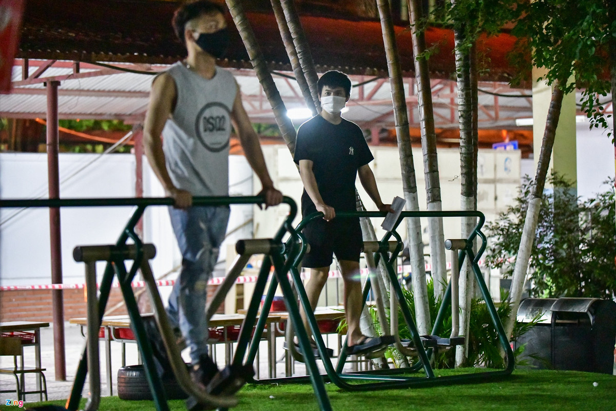 Một số người tranh thủ vận động thể thao trên các máy tập ở khu vực sân trường trong lúc chờ nhận giấy.