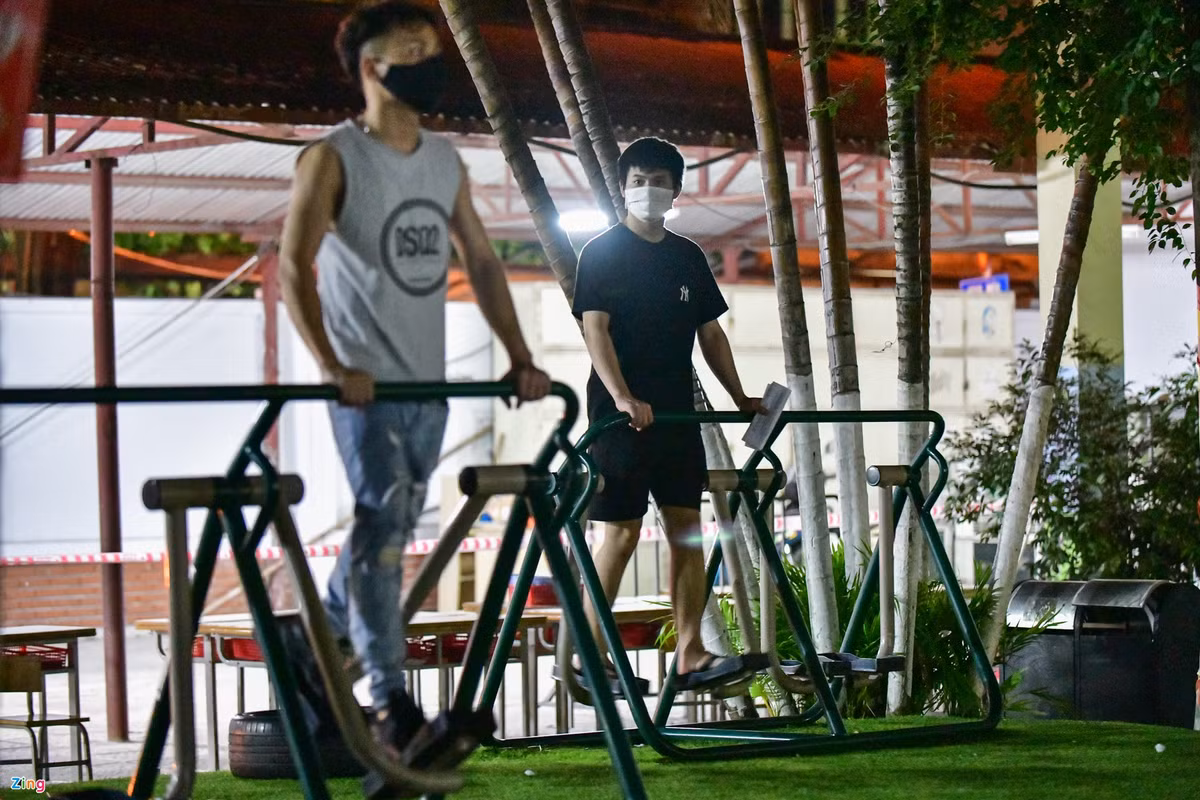 Một số người tranh thủ vận động thể thao trên các máy tập ở khu vực sân trường trong lúc chờ nhận giấy.