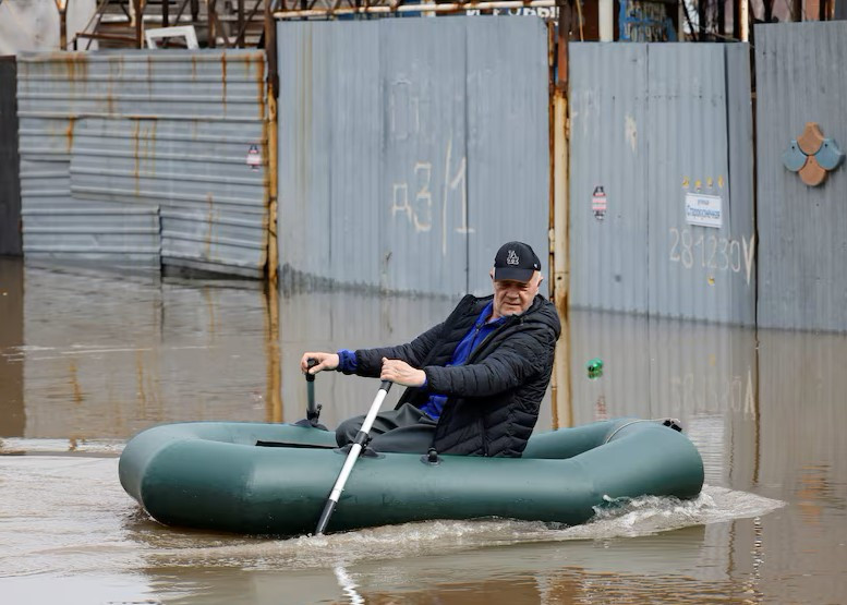 Một người đàn ông chèo thuyền bơm hơi giữa dòng nước lũ ở Orenburg.