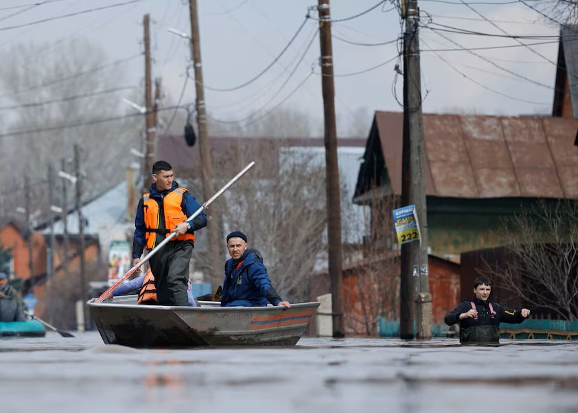 Cư dân và lực lượng cứu hộ của Bộ Tình trạng khẩn cấp Nga đi thuyền trên đường phố ngập lụt ở Orenburg, Nga.