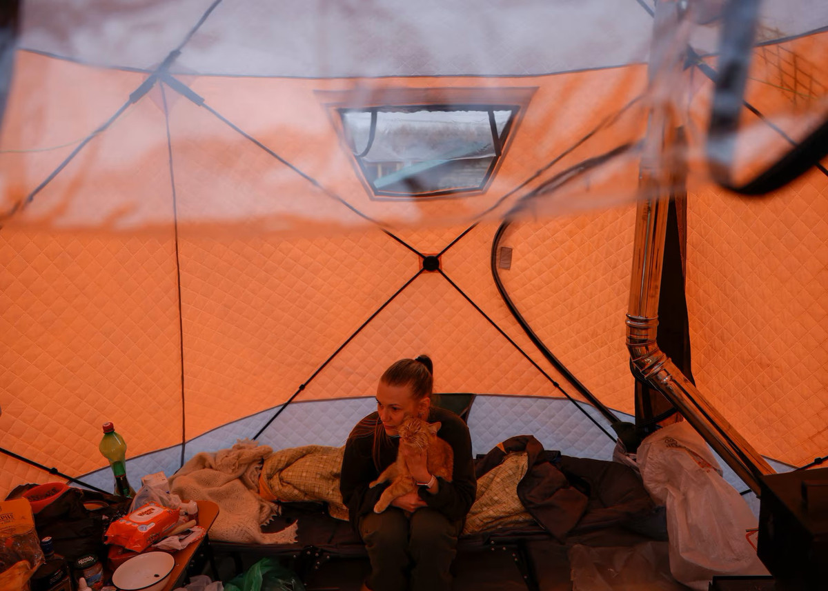 Người dân địa phương Yevgenia Perednya vuốt ve chú mèo cưng khi ngồi trong chiếc lều đặt trên nóc một ngôi nhà đang xây dở để tránh lũ.