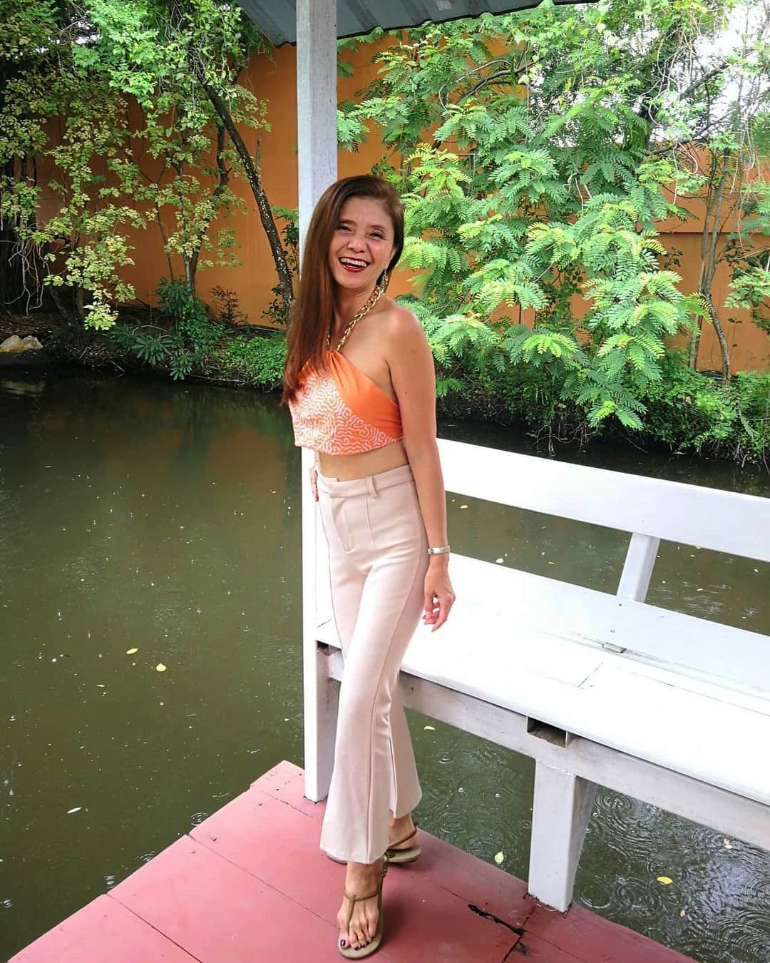 Người phụ nữ 56 tuổi trẻ trung và gợi cảm khi mix chiếc khăn làm áo yếm với quần âu trắng.