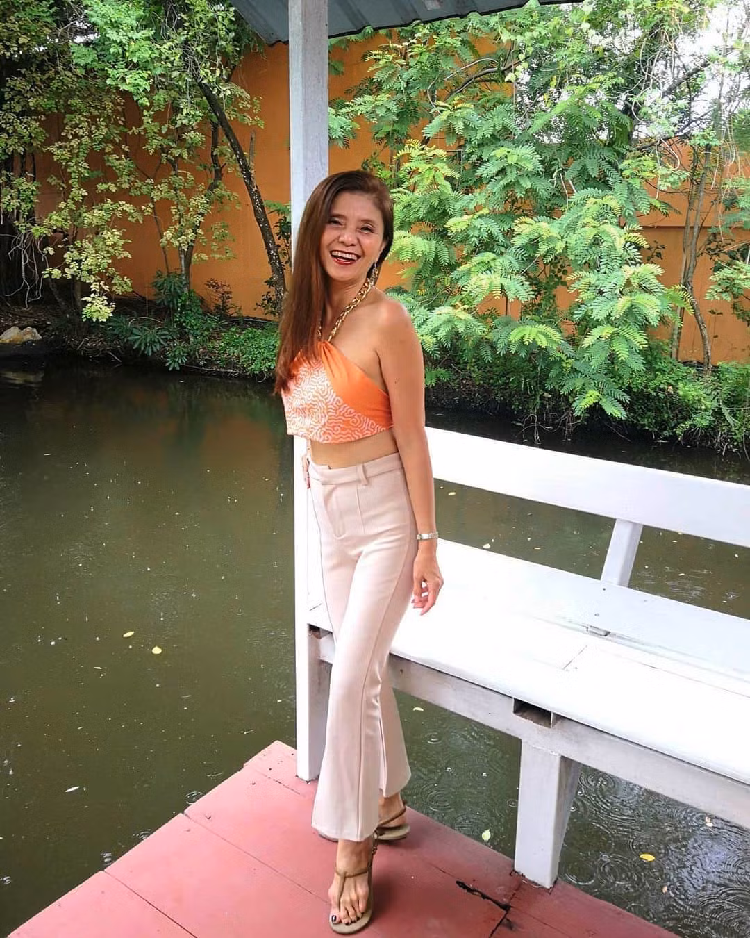 Người phụ nữ 56 tuổi trẻ trung và gợi cảm khi mix chiếc khăn làm áo yếm với quần âu trắng.