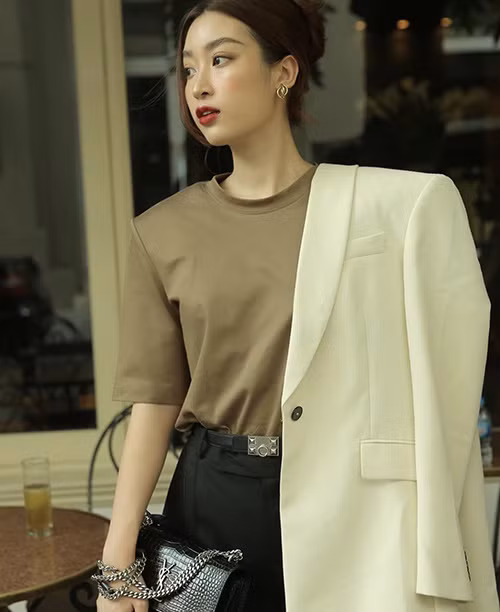 Đỗ Mỹ Linh diện áo blazer màu trắng kem phối cùng áo thun vai thô, quần âu tông đen trông khá năng động.