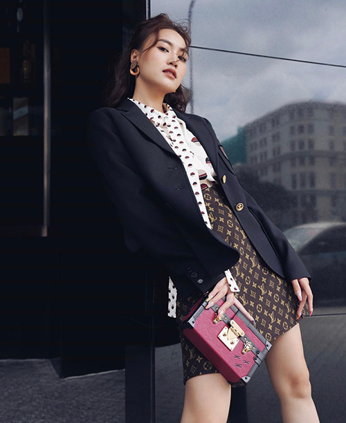 Ninh Dương Lan Ngọc hóa quý cô sang chảnh khi diện áo thắt nơ hoạ tiết chấm bi, chân váy nâu phối cùng áo vest đơn sắc và clutch xinh xắn.