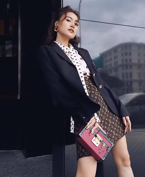 Ninh Dương Lan Ngọc hóa quý cô sang chảnh khi diện áo thắt nơ hoạ tiết chấm bi, chân váy nâu phối cùng áo vest đơn sắc và clutch xinh xắn.