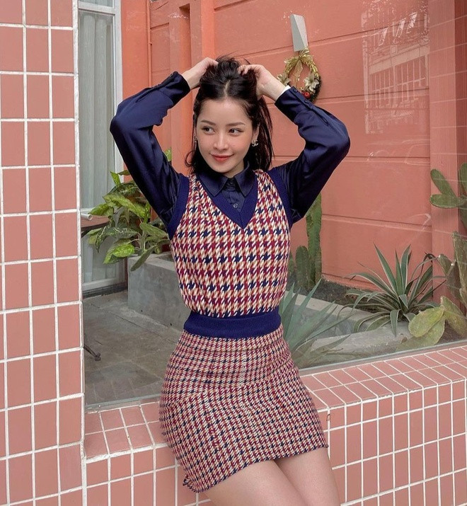 Chi Pu diện đồ đông trẻ trung và khoe được vóc dáng thon thả. Cô diện sơ mi màu xanh dương đậm cùng áo gile tông màu ấm và chiếc váy ngắn đồng họa tiết.