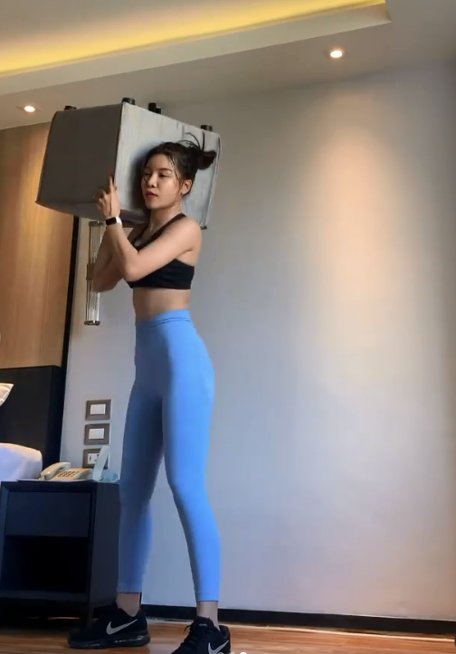 Cô tận dụng mọi thứ trong phòng, từ chiếc ghế đến lốc nước khoáng để làm dụng cụ tập luyện, đồng thời hướng dẫn cho các học viên của mình.