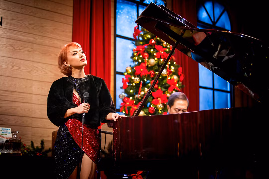 Xuân Nghi diện đồ đông màu trắng đỏ hát trong buổi lễ gần Giáng Sinh.