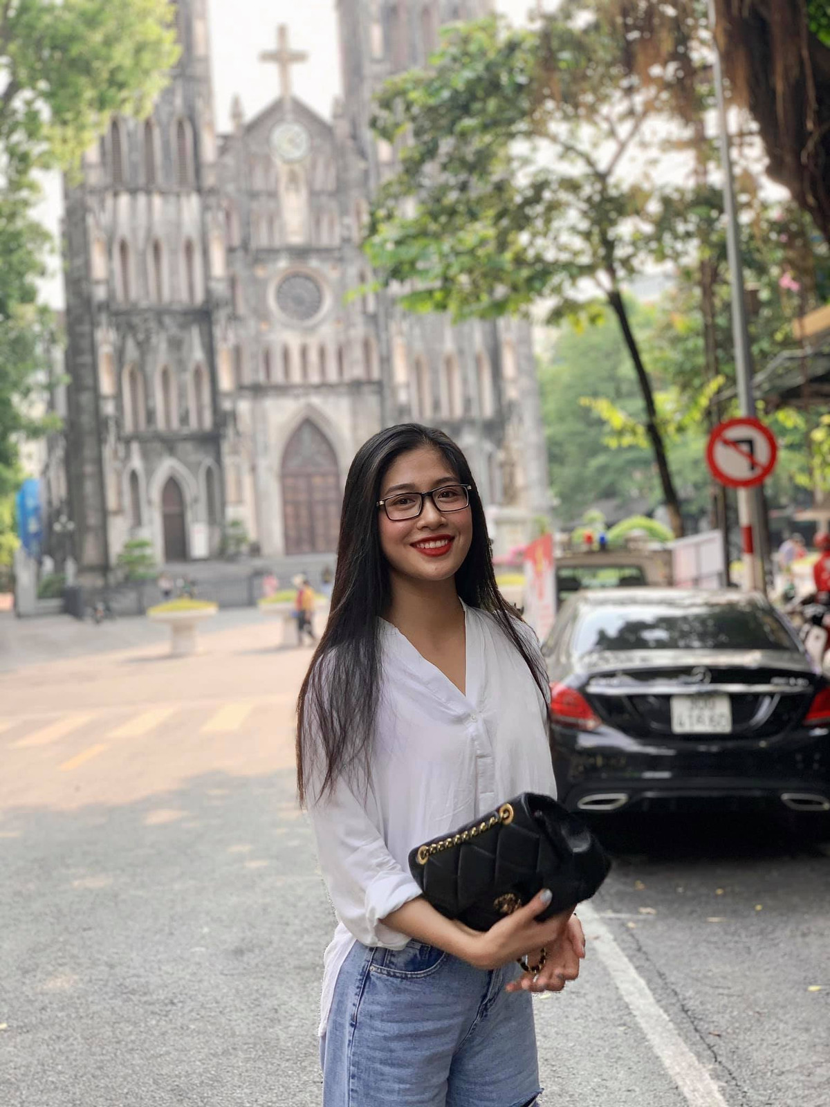 Cô gái 22 tuổi trẻ trung với áo sơ mi trắng và quần jeans năng động dạo phố.