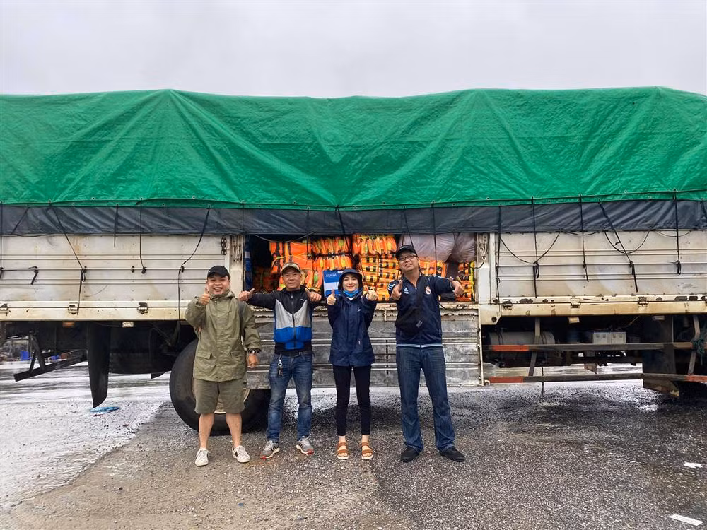 Hòa Minzy mặc áo mưa cùng anh em chuyển một xe container áo phao đến cứu trợ.