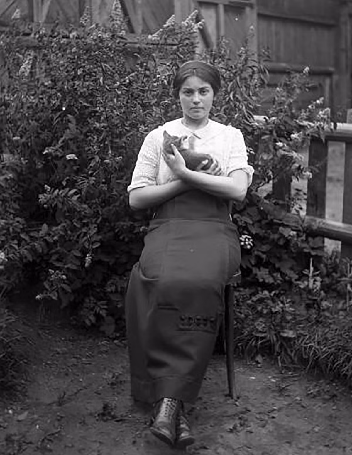 Người phụ nữ ngồi trong vườn nhà, tạo dáng chụp ảnh với mèo cưng những năm 1900.