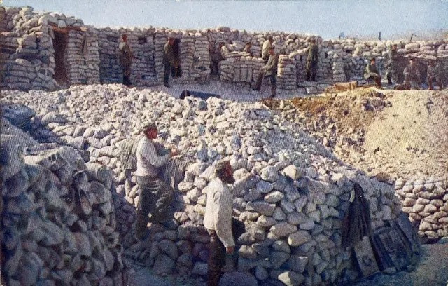 Các binh sĩ đứng xung quanh một hố bom lớn trên chiến trường Thế chiến 1.