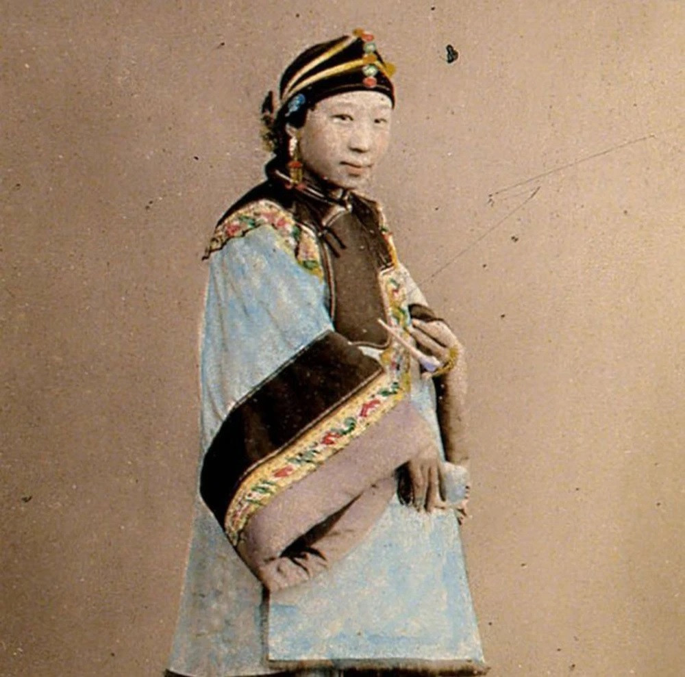 Một phụ nữ nhà Thanh mặc trang phục truyền thống, đeo nhiều phụ kiện, trang sức cho thấy địa vụ giàu sang của người này.