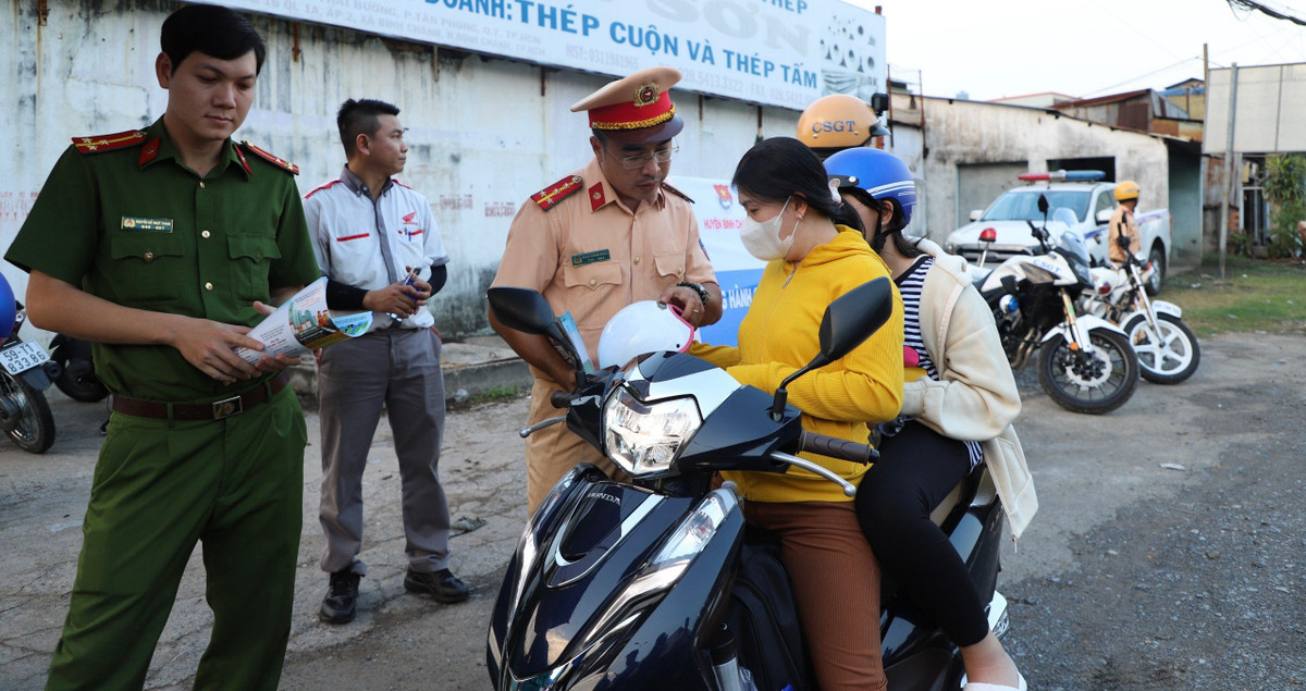 CSGT khuyến cáo người đi xe máy không sử dụng mũ bảo hiểm kém chất lượng, mất an toàn; đồng thời tặng cho người dân này mũ bảo hiểm chất lượng, tiêu chuẩn.