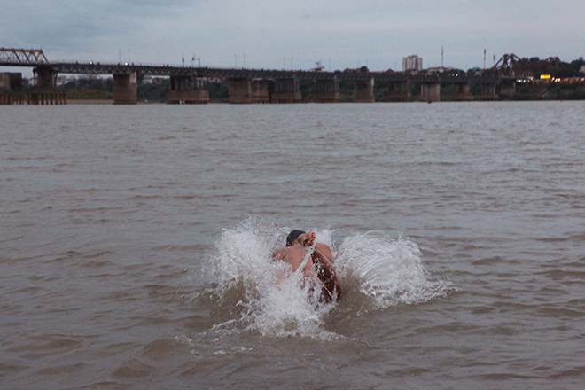 Một người khác sau khi khởi động đã lao mình xuống dòng nước lạnh, bơi ra gần giữa sông. 