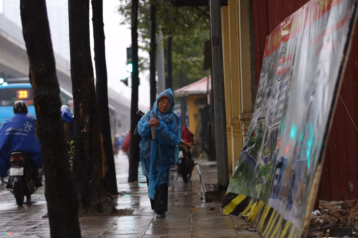Hình ảnh người dân lao động nghèo, vất vả trên các góc phố lại hiện lên mỗi khi thời tiết xấu. Trong ảnh một cụ già co ro trong chiếc áo mưa mỏng đi bộ trên đường Trần Phú (quận Hà Đông).