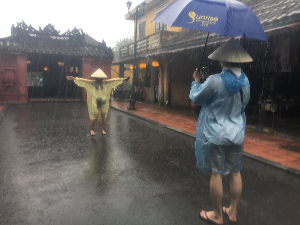 Khách du lịch thích thú chụp ảnh trongmưa lớn tại Chùa Cầu.