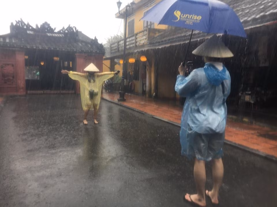 Khách du lịch thích thú chụp ảnh trongmưa lớn tại Chùa Cầu.