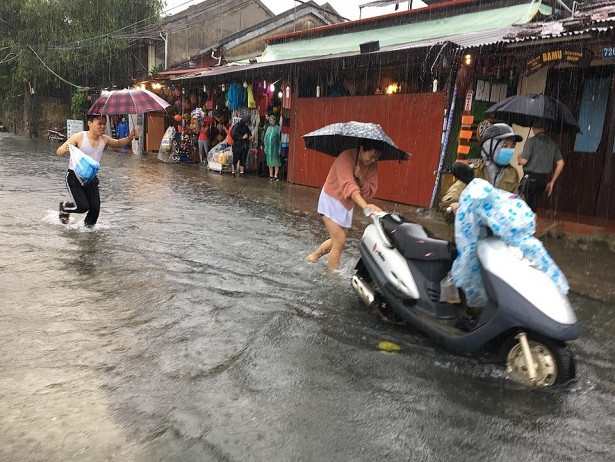 Người dân đẩy xe chết máy do lội nước ngập trong phố cổ Hội An.
