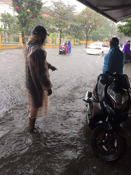 Người dân đợi trong vỉa hè chờ nước rút vì đường ngập không thể đi lại.