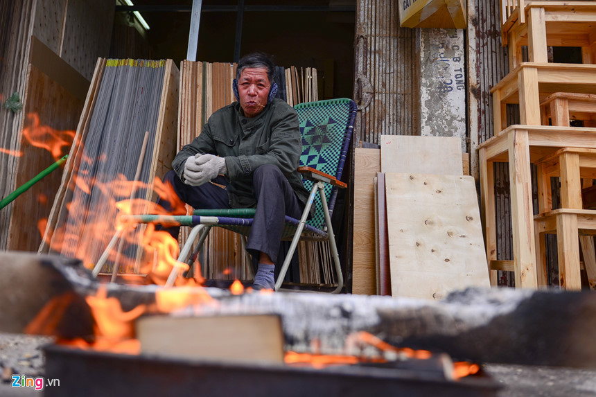 Ông Duy Thắng ở đường La Thành tận dụng những mảnh gỗ bỏ đi để sưởi ấm chống giá rét. “Trời lạnh, khách mua hàng ít hơn hẳn nhưng tôi vẫn phải ngồi ngoài này để đón khách”