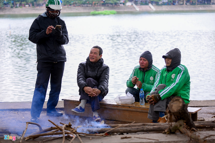 Một nhóm người chạy xe ôm, xe ba gác khi không có khách ngồi sưởi ấm bên hồ Đắc Di. “Tuy ngồi gần hồ hơi lạnh nhưng có khách gọi là chúng tôi đi được luôn”, một lái xe chia sẻ.