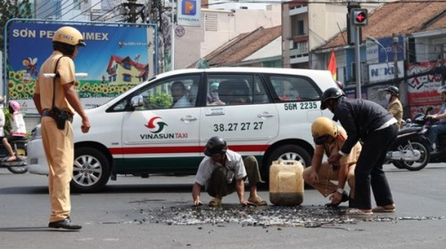 Hai CSGT thuộc đội CSGT Tân Sơn Nhất đang chốt chặn trên đường chạy tới đỡ xe lên và thu gom cá vào can nhựa giúp người dân