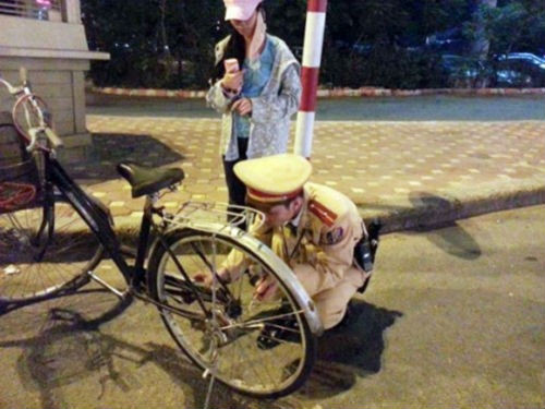Chú cảnh sát dừng lại sửa xe đạp giúp người đi đường.