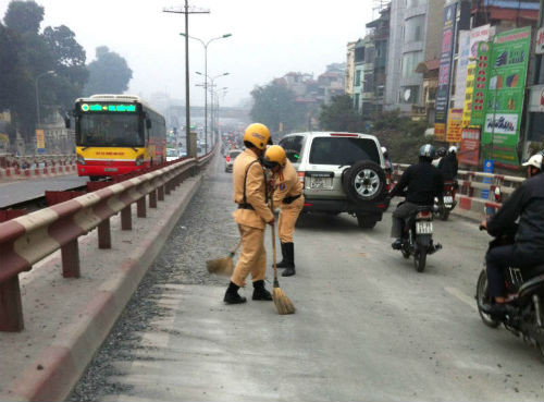 Lực lượng cảnh sát giao thông làm nhiệm vụ tại khu vực cầu vượt Ngã Tư Vọng nhanh chóng quét dọn, thu gom, đá, sỏi do các phương tiện vận chuyển làm rơi vãi nhằm đảm bảo an toàn cho người và phương tiện qua lại. 