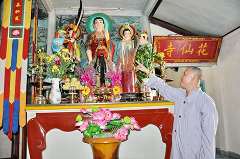 Đại đức Thích Chơn Đạo giới thiệu thư tịch cổ đặt trong bình tròn trên một bàn thờ trong chùa Hoa Tiên.