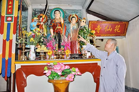 Đại đức Thích Chơn Đạo giới thiệu thư tịch cổ đặt trong bình tròn trên một bàn thờ trong chùa Hoa Tiên.