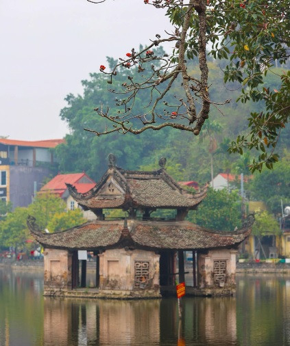 Nhành hoa gạo sà xuống trước thủy đình trên hồ. Đây là một kiến trúc đặc sắc, hình ảnh tiêu biểu của Chùa Thầy. Thủy đình được sử dụng để múa rối nước, hiện vẫn còn sử dụng trong dịp lễ hội.