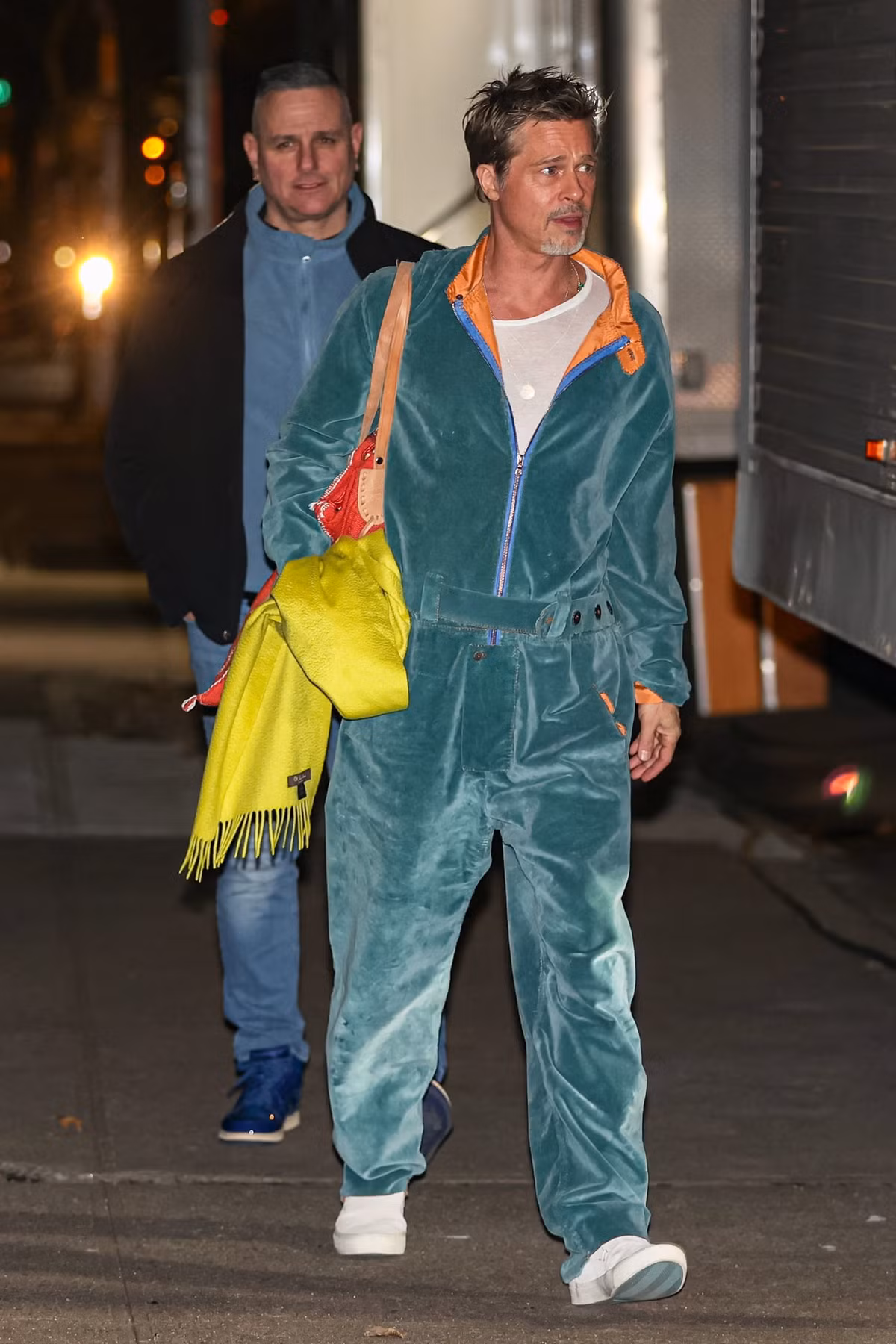 Bộ jums vải nhung màu xanh được coi là một trong những bộ trang phục trẻ trung và phá cách nhất của nam diễn viên Hollywood. Để tổng thể trở nên nổi bật hơn, Brad Pitt dùng túi màu cam đỏ, khăn quàng xanh neon của Loro Piana.