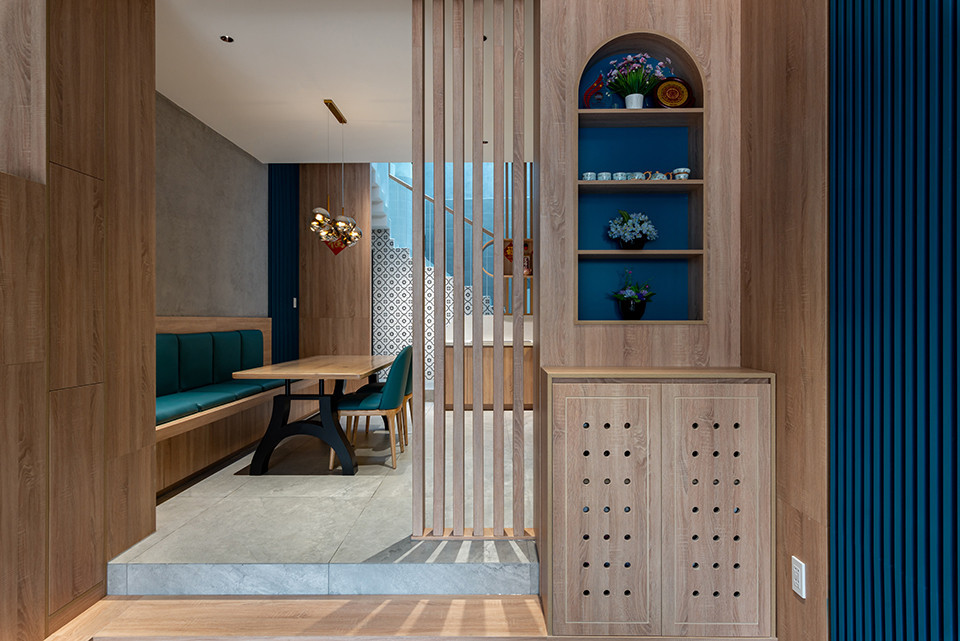 Tầng trệt là nhà để xe, khu thờ nhỏ, bếp và phòng ăn, nhà kho, sân sau và nhà vệ sinh. Lầu 1 là phòng khách và khu thông tầng mở rộng để kết nối với tầng trệt dễ dàng. Khi muốn có không gian riêng tư để xem phim, nghe nhạc, gia chủ chỉ cần đóng cửa lại. Sự phân lớp màu sắc xám - xanh dương - gỗ sáng màu tạo chiều sâu cho không gian nhà.