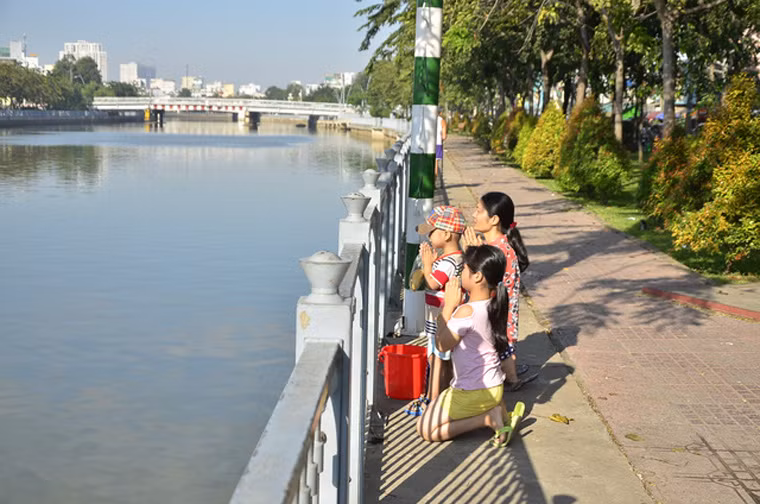 Cả gia đình thành tâm trong lễ thả cá tại kênh Nhiêu Lộc - Thị Nghè.