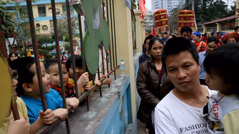 Học sinh một trường mầm non háo hức bám rào xem đoàn rước kiệu tại lễ hội Phủ Chúa (phường Xuân Đỉnh, quận Bắc Từ Liêm, Hà Nội).