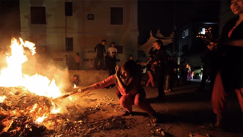 Hơi nóng hầm hập toả ra từ đống lửa khiến việc châm hương rất khó khăn.