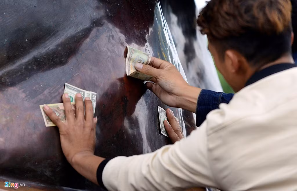 Đầy đủ mệnh giá, các loại tiền khác nhau được du khách xoa lên phần thân bức tượng đồng.