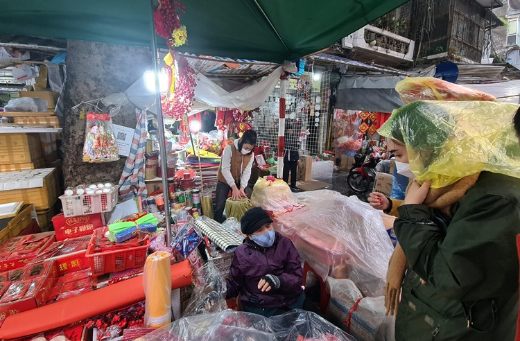 Cô gái này đến phố Hàng Mã mua sắm đồ trang trí Tết nhưng quên mang theo áo mưa, đành phải dùng túi ni lông che đầu.
