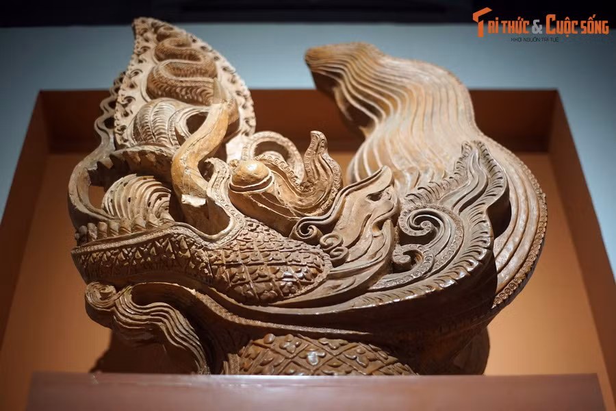 Làm bằng đất nung, hiện vật thể hiện đầu rồng ở tư thế vận động, bờm và mào chuyển động mạnh với nhiều khúc uốn lượn, hướng về phía trước. Đầu rồng có má phình rộng, miệng mở to, ngậm ngọc báu, răng được thể hiện rõ ràng. Mũi và môi trên biến thành mào lửa hình lôi văn chữ S...